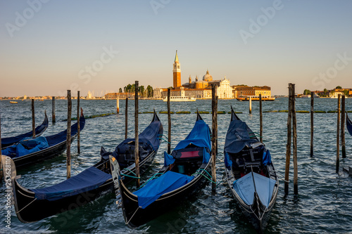 Gondolas moored by Saint Mark square with San Giorgio di Maggiore church in the background in Venice, Italy © SkandaRamana