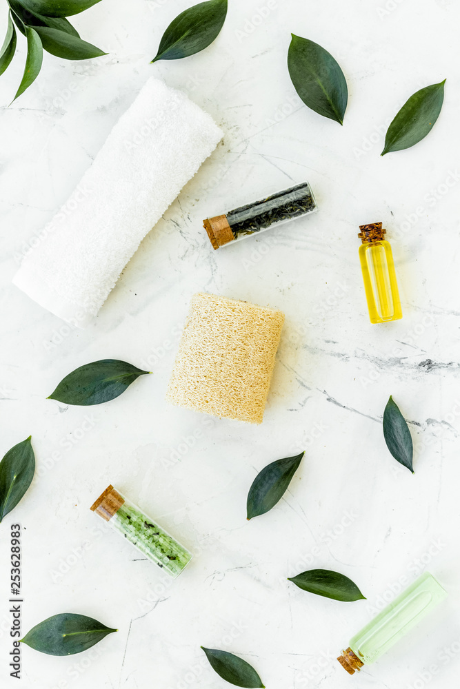 Spa composition with essential tea tree oil. Fresh tea tree leaves, natural cosmetics, towel on white stone background top view Spa composition with essential tea tree oil. Fresh tea tree leaves, natural cosmetics, towel on white stone background top view