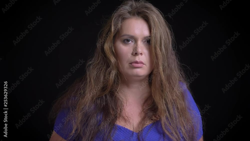Closeup portrait of middle aged attractive caucasian female being sad and depressed while looking at camera with background isolated on black Closeup portrait of middle aged attractive caucasian female being sad and depressed while looking at camera with background isolated on black