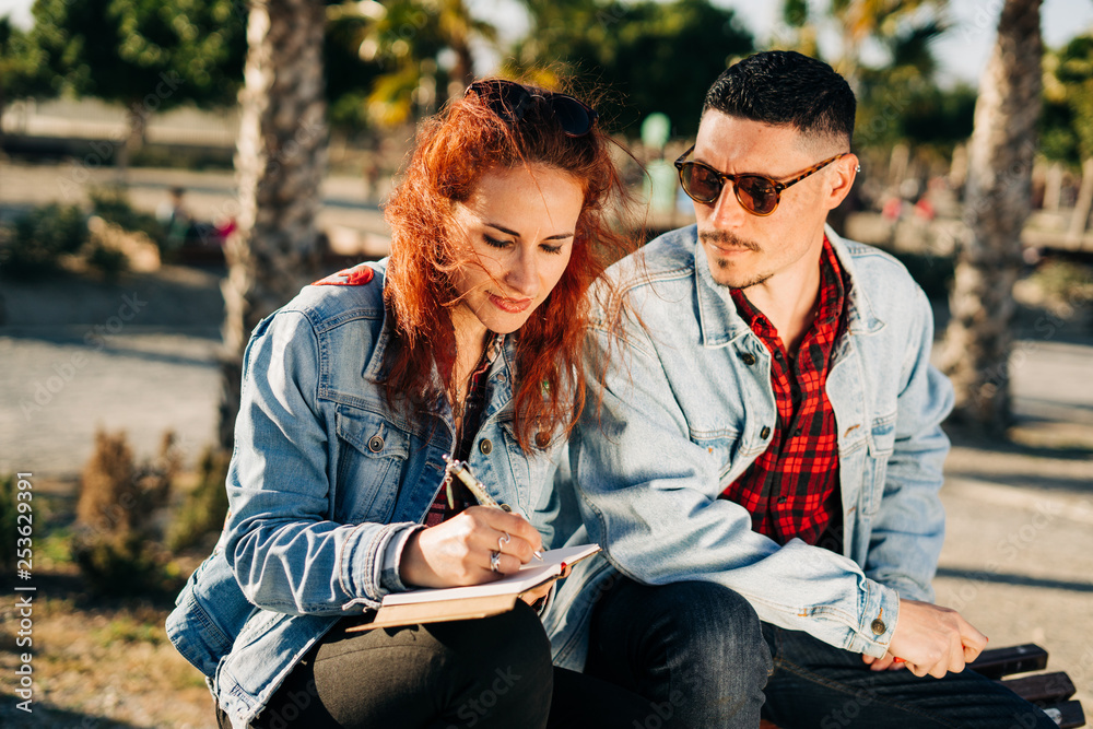 Happy young couple in love sitting in a park reading a book. Happy young couple in love sitting in a park reading a book.
