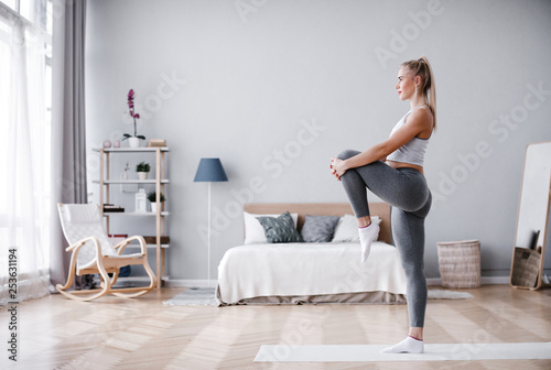 Full length portrait of attractive young woman working out at home, doing pilates exercise on mat. © BestForYou