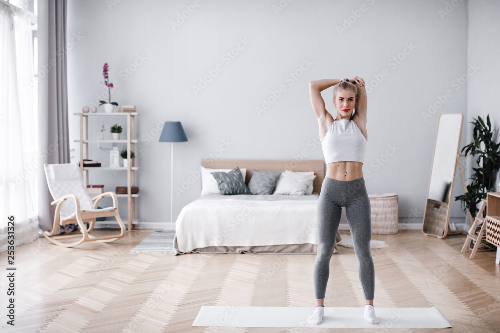 Training at home. Beautiful athletic woman doing exercises in the room.
