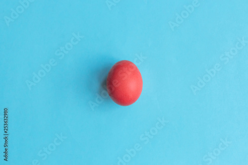 Trend colored pink chicken egg on a blue pastel minimalistic background