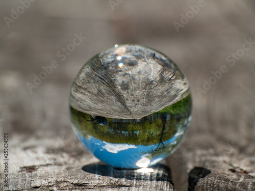 Landscape reflected in a crystal ball on an old wooden table