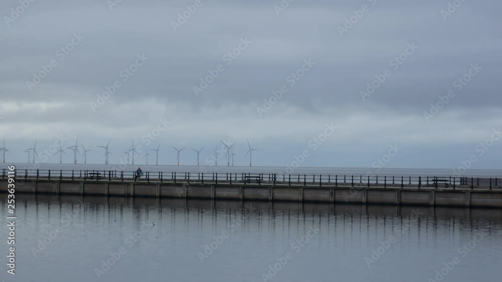 People walk the promenade of the seaside town New Brighton with Wind Turbines People walk the promenade of the seaside town New Brighton with Wind Turbines