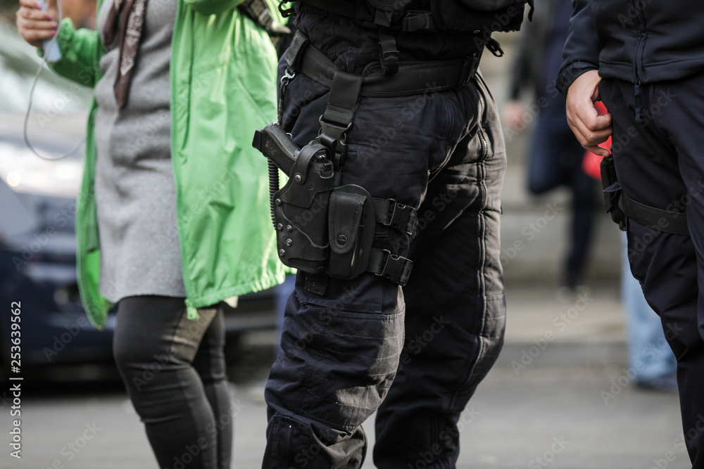 Details of the security kit of a riot police officer, including handcuffs, 9mm handgun, radio station and baton Details of the security kit of a riot police officer, including handcuffs, 9mm handgun, radio station and baton