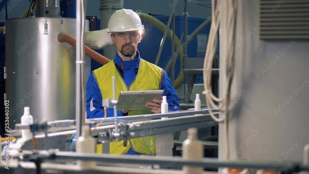 Conveyor belt with small plastic bottles is being observed by a specialist Conveyor belt with small plastic bottles is being observed by a specialist