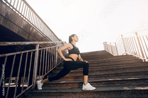 Young sexy woman jogger athlete training on road. Concept of healthy lifestyle. Female fitness model working out outdoor in city on the steps.