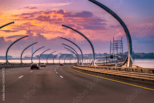 Modern highway. Road with cars in the evening. Highway at sunset. Cars drive in the direction of the sunset. Highway. Highway at sunset.