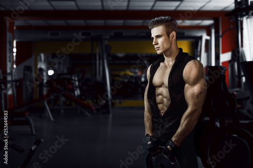 Muscular model young man exercising in gym. Portrait of sporty strong muscle. Fitness trainer. Sport workout bodybuilding motivation concept. Sexy naked torso  six pack abs. Male flexing his muscles.