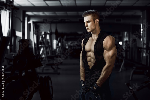 Muscular model young man exercising in gym. Portrait of sporty strong muscle. Fitness trainer. Sport workout bodybuilding motivation concept. Sexy naked torso, six pack abs. Male flexing his muscles.