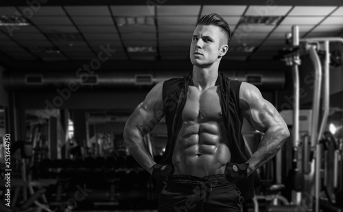 Muscular model sports young man exercising in gym. Black and white portrait of strong muscle. Fitness trainer. Sport workout bodybuilding motivation concept. Sexy torso.