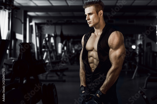 Muscular model sports young man exercising in gym. Portrait of sporty healthy strong muscle. Fitness trainer. Sport workout bodybuilding motivation concept. Sexy torso. © KDdesignphoto