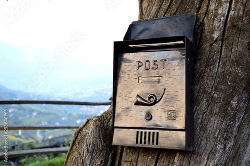 Postzustellung auf dem Land - alter Postbriefkasten an einem Baum photo