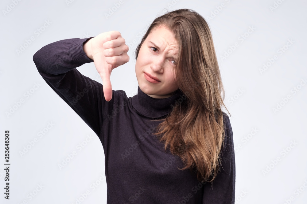 Pretty young woman thumbing down, isolated on white background. Pretty young woman thumbing down, isolated on white background.