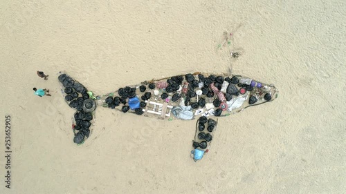 Drone zenital video of an art made of whale-shaped garbage. People walk around the beach. Brazilian Beach.  photo