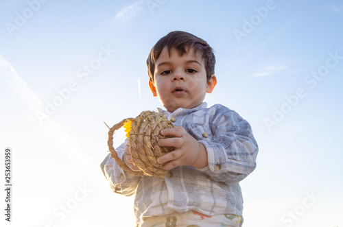 portrait of two years old toddler holding bascet with two easter eggs - golden hour photo