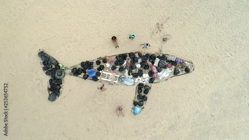 Drone zenital video of people lying on the sand with their arms outstretched around an art made of whale-shaped garbage. People walk around the beach. Brazilian Beach.  photo