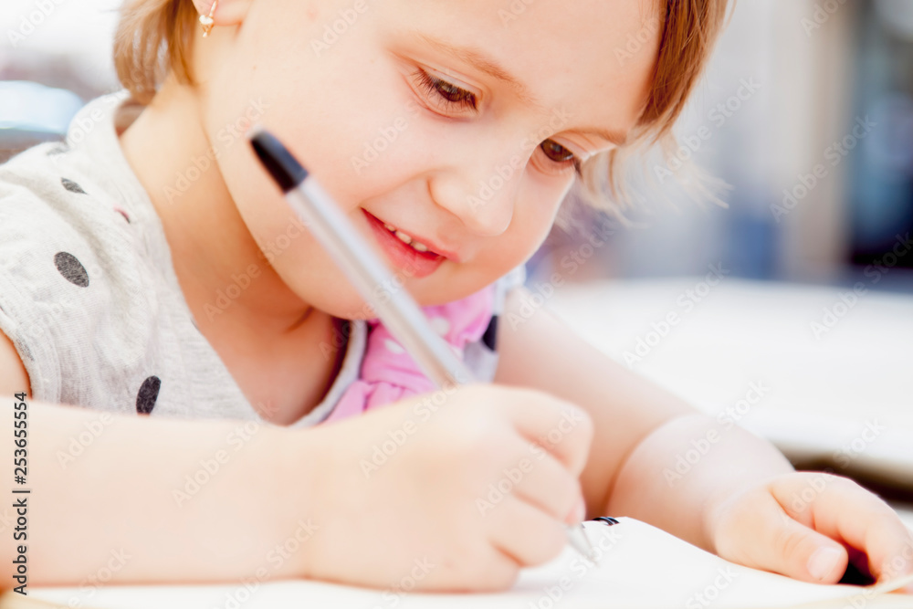 Funny portrait happy cute child girl laughing and writing a letter. Positive emotion, education and happy childhood concept. Funny portrait happy cute child girl laughing and writing a letter. Positive emotion, education and happy childhood concept.
