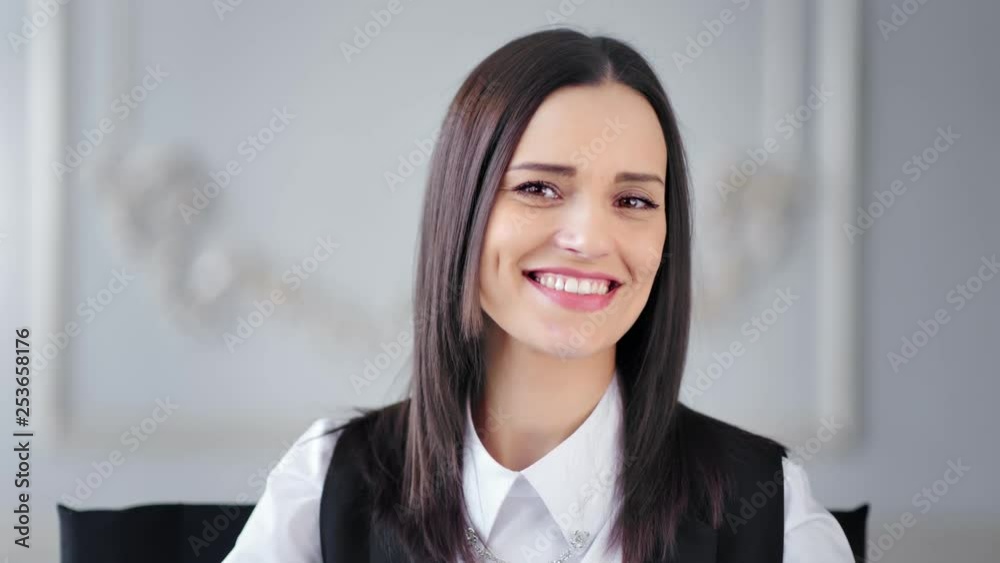 Portrait of beautiful young smiling brunette businesswoman posing and looking at camera