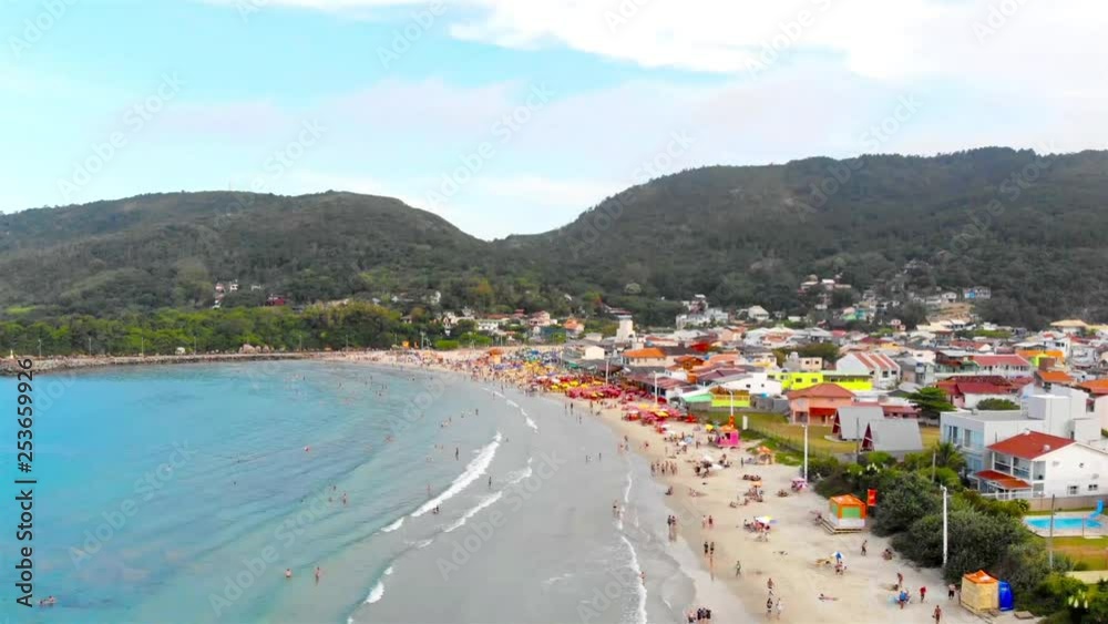 An aerial view of a beach in Brazil full of people with green hills in back - Crane Down An aerial view of a beach in Brazil full of people with green hills in back - Crane Down