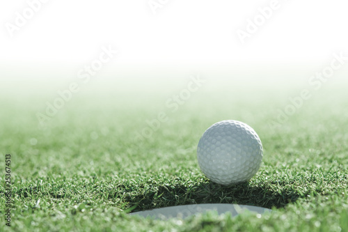 Golf ball and golf hole on green grass with copy space