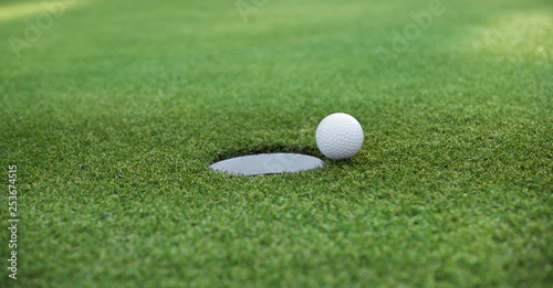 Golf ball and golf hole on green grass with copy space