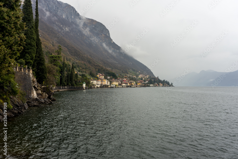 Italy, Varenna, Lake Como, a large body of water with a mountain in the background Italy, Varenna, Lake Como, a large body of water with a mountain in the background