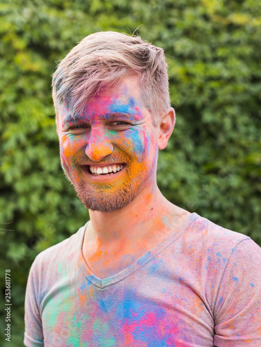 Holi festival, happiness, people concept - young dirty man at the indian festival over the nature background