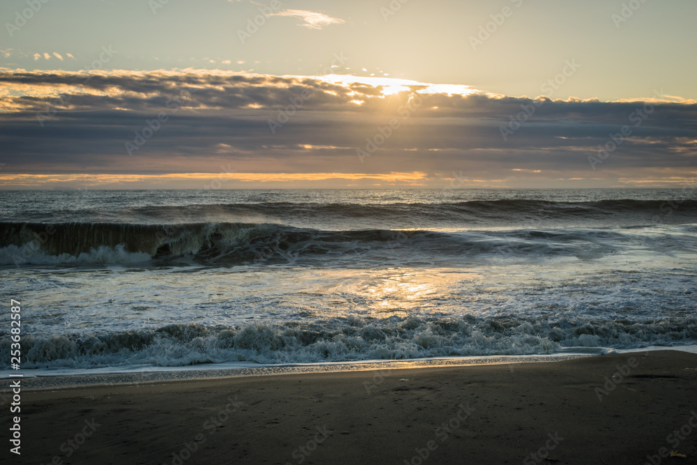 Waves Breaking on the Sandy Shore at Sunrise