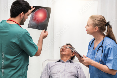 Doctor team work with x ray film image of the senior adult patient lying on the bed in the hospital ward room. Medical group teamwork and healthcare person staff service. photo