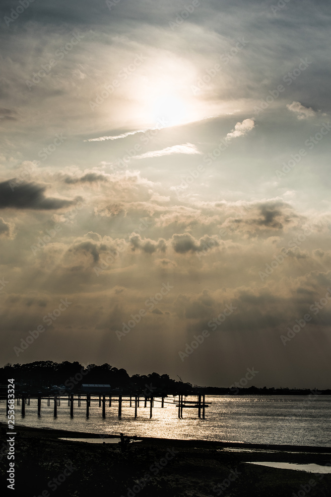 Silhouette of the River Bank at Golden Hour with Sunrays Shining through the clouds Silhouette of the River Bank at Golden Hour with Sunrays Shining through the clouds