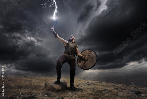 Medieval warrior berserk Viking with axe catch the lightning. Concept historical dramatic photo