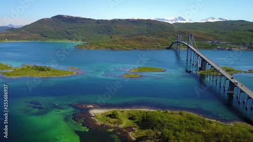 Aerial, pan, drone shot, of turquoise sea and cars, on the Tjeldsund Bridge, on a sunny, summer day, in the Lofoten islands, in Sørvik, Norway photo