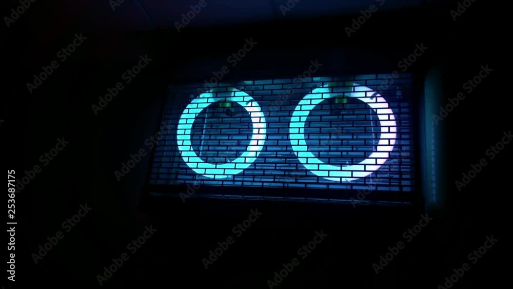 Slow push in dark black room with two neon blue UV lights behind cage in bug zapper system.