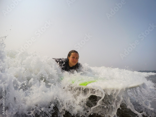 Female beginner surfer is learning how to surf in the Pacific Ocean. Taken in Tofino, Vancouver Island, British Columbia, Canada. © edb3_16