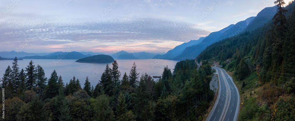 Fototapeta premium Aerial panoramic view of the scenic highway surounded by the Beautiful Canadian Mountain Landscape during a summer sunrise. Taken in Sunset Beach, North of Vancouver, British Columbia, Canada.