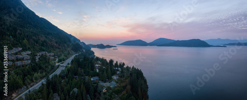 Aerial panoramic view of the scenic highway surounded by the Beautiful Canadian Mountain Landscape during a summer sunrise. Taken in Sunset Beach, North of Vancouver, British Columbia, Canada.