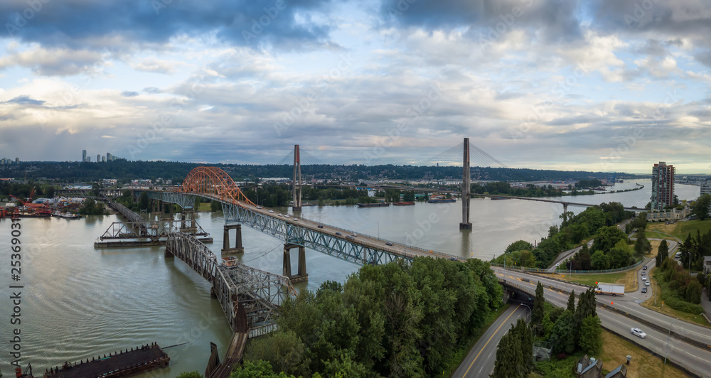 Aerial panoramic view of Pattullo and Skytrain Bridge going across Fraser River duing a cloudy evening before sunset. Taken in New Westminster, Vancouver, BC, Canada. Aerial panoramic view of Pattullo and Skytrain Bridge going across Fraser River duing a cloudy evening before sunset. Taken in New Westminster, Vancouver, BC, Canada.