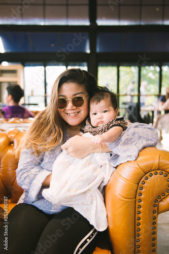 Portrait of young mother and her newborn baby sitting on sofa  in a nice cafe  Happy childhood  a friendly family.