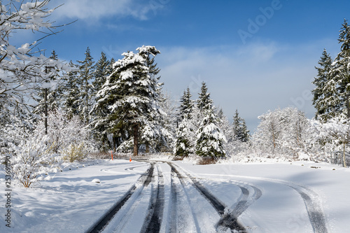 Challenging travel in a beautiful snow covered parking lot, snow covered trees, blue ski, and white clouds