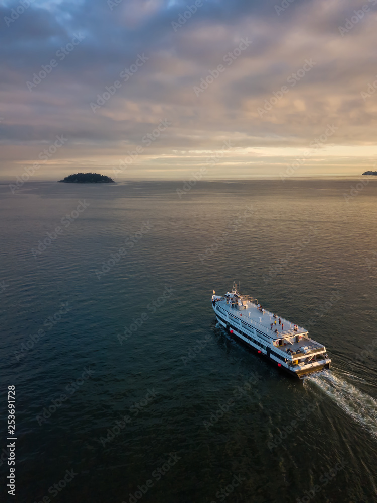 Aerial view of a ferry boat in the ocean during a vibrant cloudy sunset. Taken in Horseshoe Bay, West Vancouver, British Columbia, Canada. Aerial view of a ferry boat in the ocean during a vibrant cloudy sunset. Taken in Horseshoe Bay, West Vancouver, British Columbia, Canada.