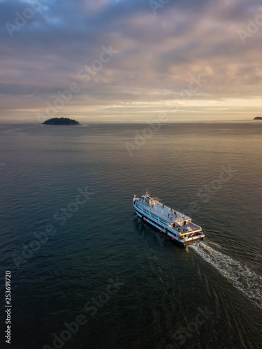 Aerial view of a ferry boat in the ocean during a vibrant cloudy sunset. Taken in Horseshoe Bay, West Vancouver, British Columbia, Canada.