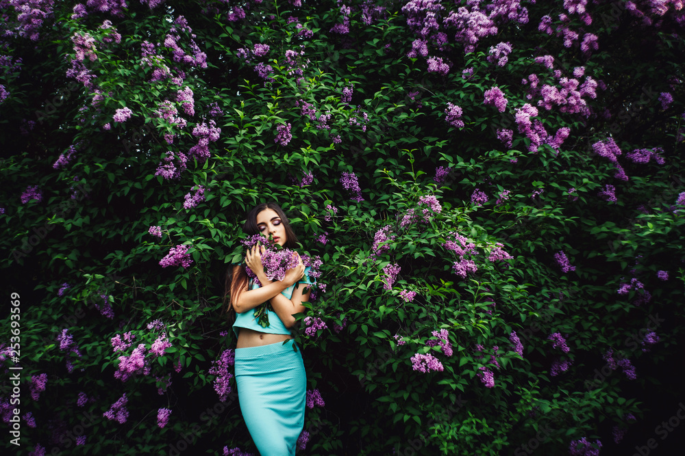 Wonderful spring. Cute young girl enjoys nature among the blossoming lilac and holds a bouquet. Wonderful spring. Cute young girl enjoys nature among the blossoming lilac and holds a bouquet.