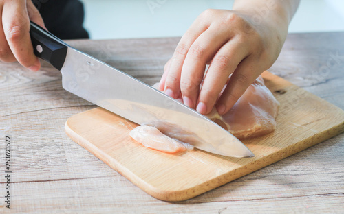 Hand cutting Chicken on wooden chopping board. photo