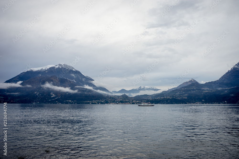 Italy, Varenna, Lake Como, boat in a serene scene with snow cap mountain