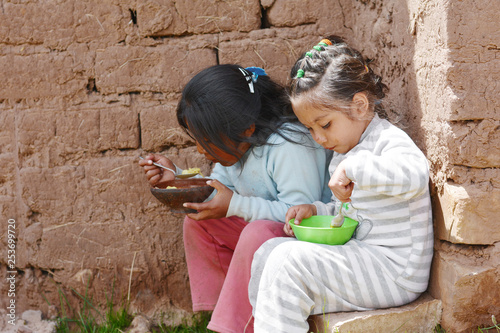 Quadro su tela Native american girls eating. Adobe bricks background.