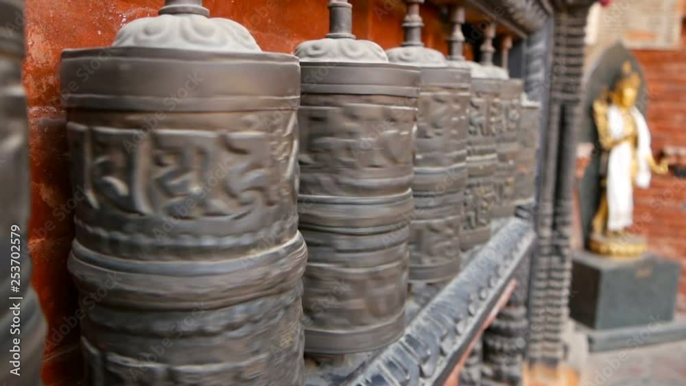 Row of aged religious prayer wheels or drums with mantra Om Mani Padme Hum in yard of temple, Durbar Square, Nepal, Kathmandu. Tibetian buddhism Row of aged religious prayer wheels or drums with mantra Om Mani Padme Hum in yard of temple, Durbar Square, Nepal, Kathmandu. Tibetian buddhism