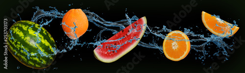 fruit - orange and watermelon in water on an isolated green and black background