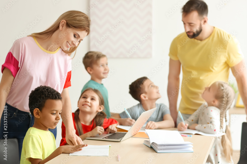 Teachers helping children with homework in classroom at school